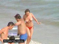 The shameless female in red bikini is eager to demonstrate naked tits to all the people at the beach.