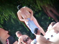 The beautiful nudist woman is staying under the hot sun rays and does not suspect that her tits and bushy nub get spied on the camera
