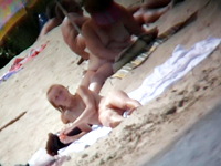 The pretty nudist woman was sitting on the beach and our hunter was trying to see the nude pussy between her nice legs